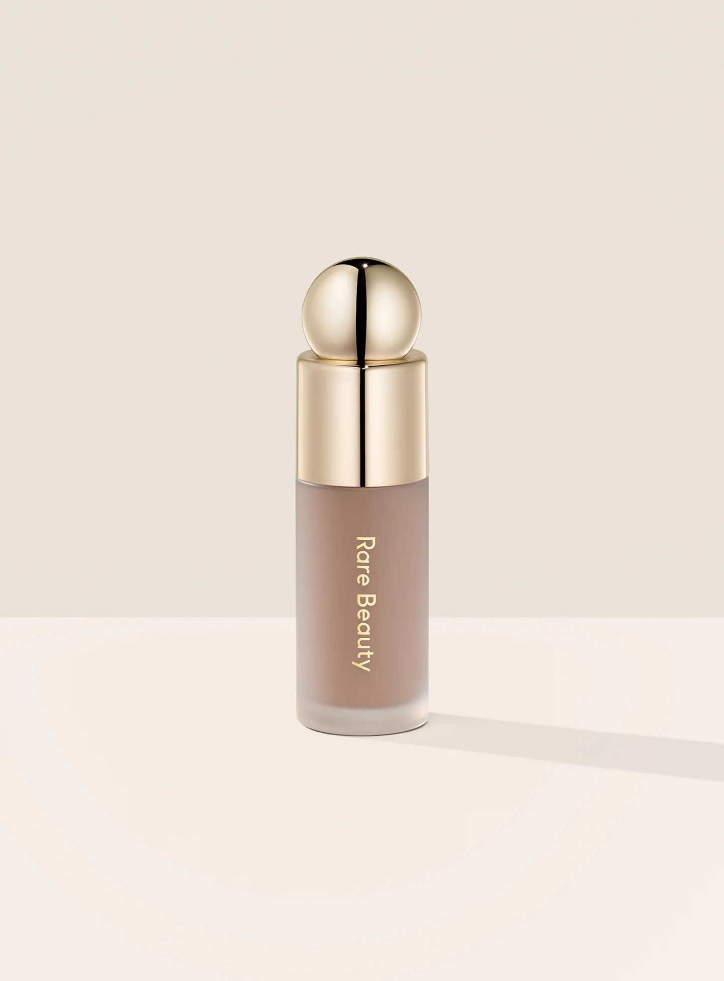Rare Beauty Soft Pinch Liquid Contour in Gentle – a sleek frosted bottle with a doe-foot applicator containing a light cool brown liquid.